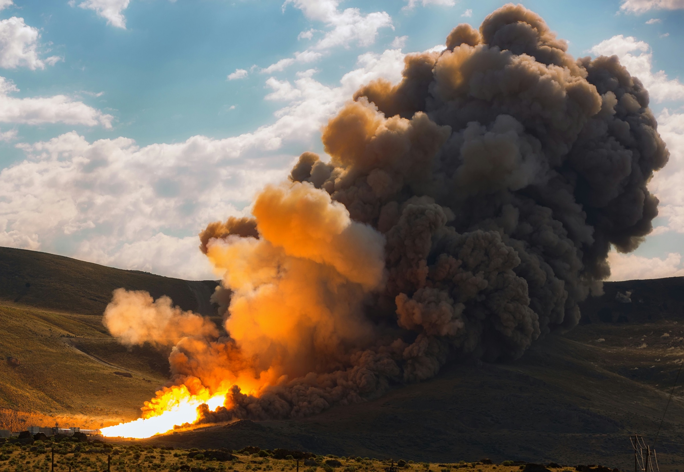 Static-fire test of a solid rocket motor, with an orange flame and a plume of smoke